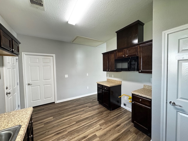 kitchen featuring sink, dark brown cabinetry, light stone counters, dark wood-type flooring, and a textured ceiling