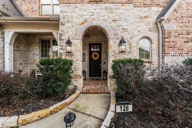 property entrance featuring stone siding and brick siding