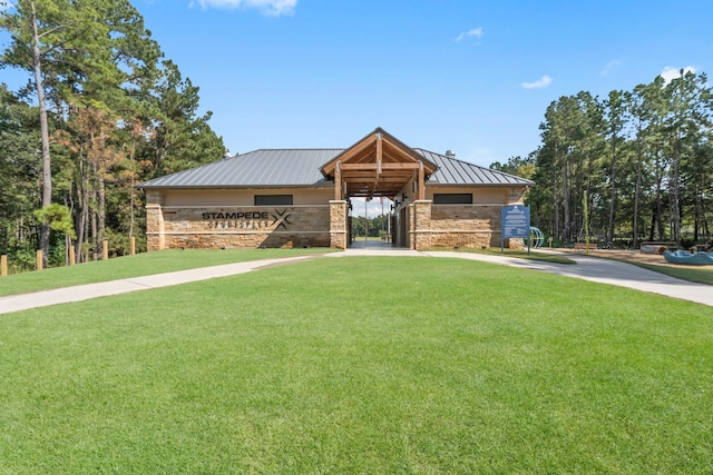 view of front facade with an outbuilding, concrete driveway, a standing seam roof, metal roof, and stone siding