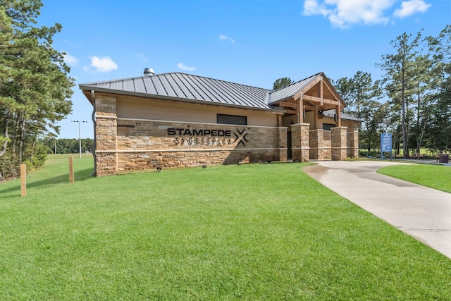 view of front of house with stone siding, a standing seam roof, metal roof, and a front lawn