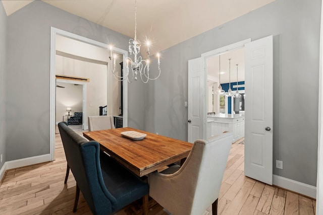 dining area with a chandelier, light wood-style flooring, and baseboards