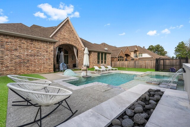 view of swimming pool featuring a fenced backyard, a pool with connected hot tub, and a patio