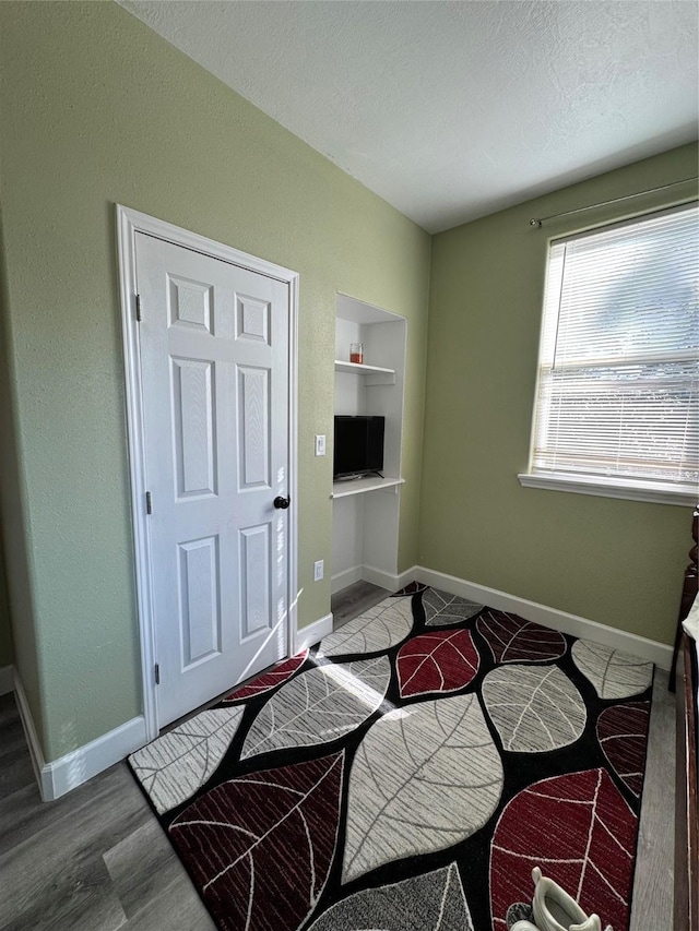 interior space with hardwood / wood-style flooring, a textured ceiling, and built in shelves