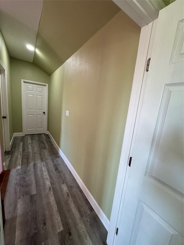 corridor with lofted ceiling, baseboards, and dark wood-style flooring