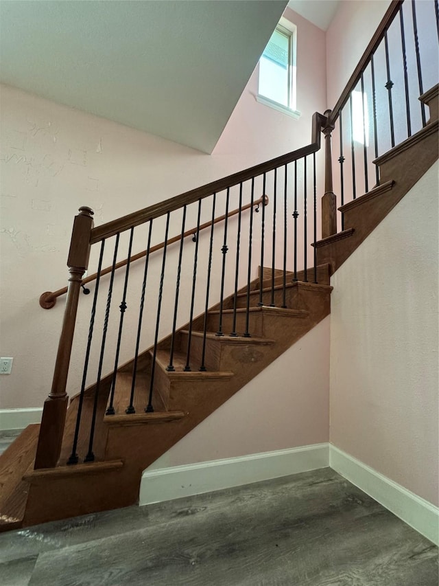 stairs featuring wood finished floors, baseboards, and a towering ceiling