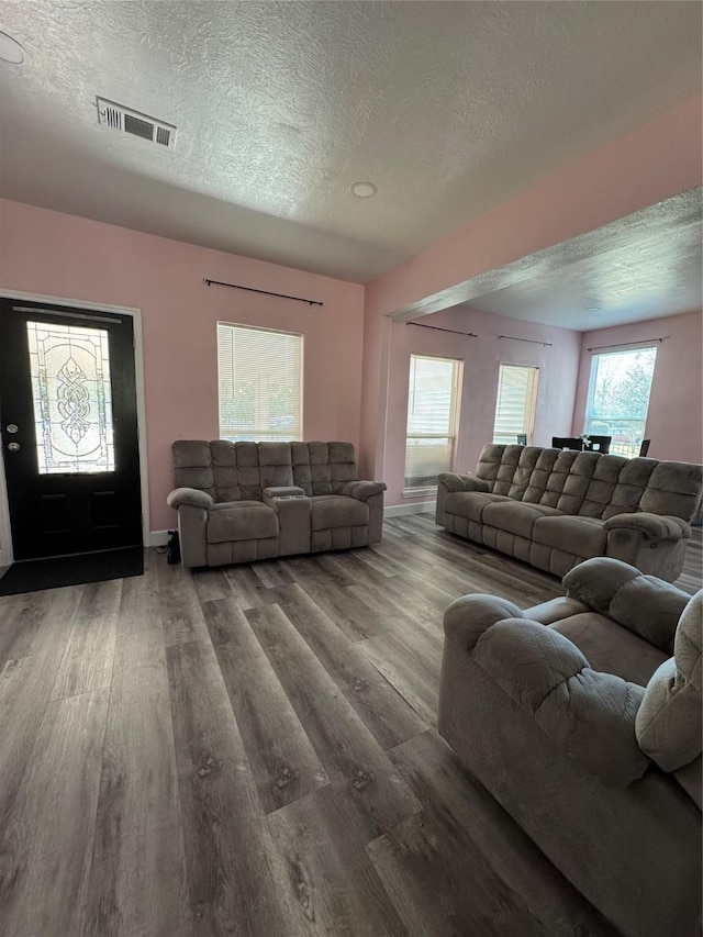 living area with visible vents, a textured ceiling, and wood finished floors