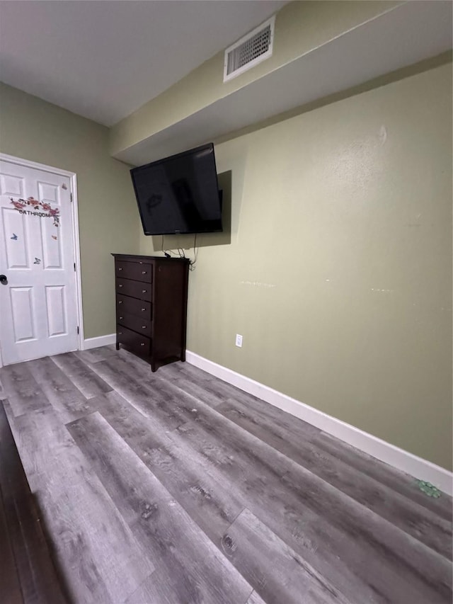 unfurnished bedroom featuring wood finished floors, visible vents, and baseboards