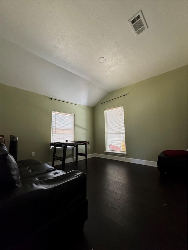 bedroom with baseboards, visible vents, vaulted ceiling, dark wood-type flooring, and a textured ceiling