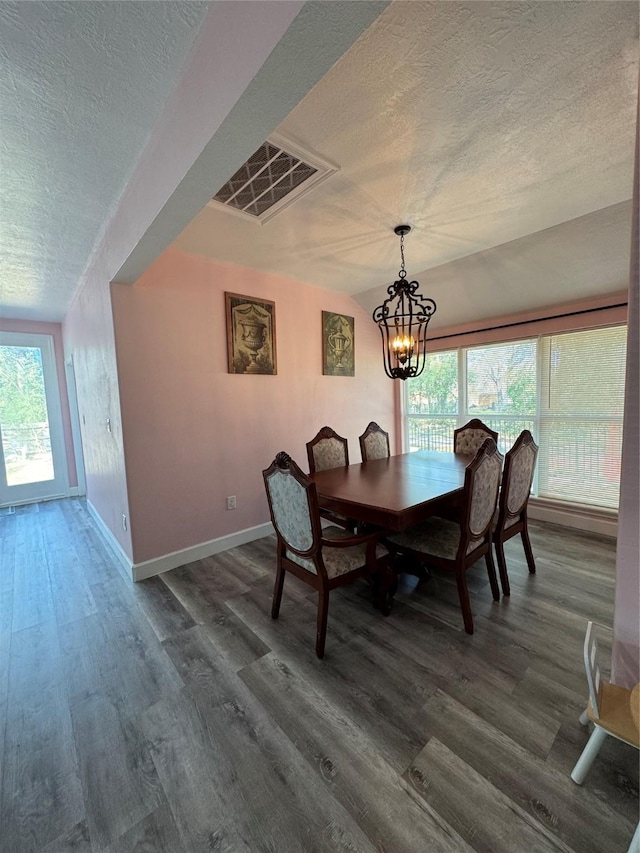 dining area featuring dark hardwood / wood-style flooring, a textured ceiling, and a notable chandelier