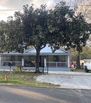 view of front of house with fence, covered porch, and driveway