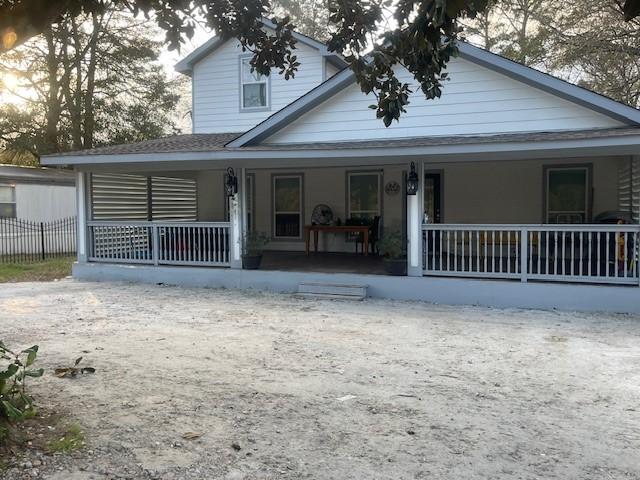 farmhouse inspired home with covered porch and fence