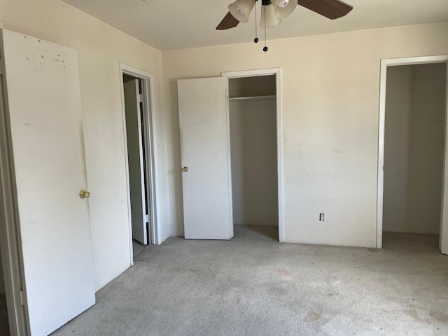 unfurnished bedroom with ceiling fan, light carpet, and two closets