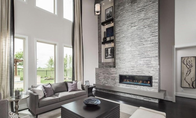 living room with hardwood / wood-style flooring, plenty of natural light, a fireplace, and a high ceiling