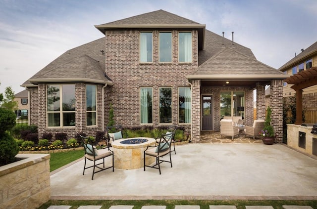 rear view of property with exterior kitchen, a patio, and an outdoor fire pit