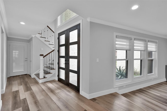 entryway featuring ornamental molding, light hardwood / wood-style floors, and french doors