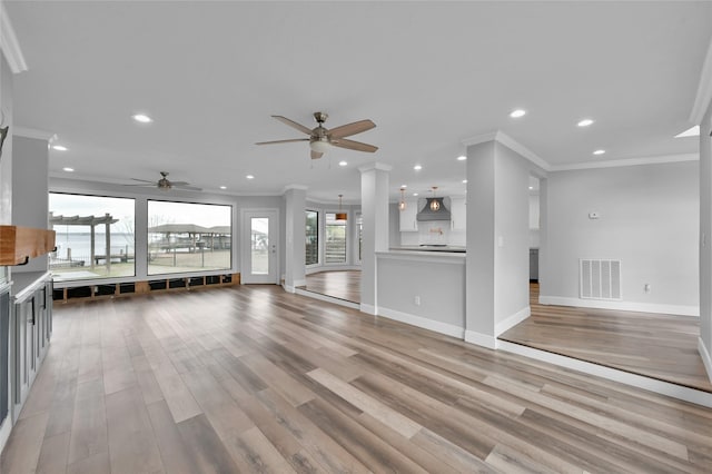 unfurnished living room with crown molding, ceiling fan, and light hardwood / wood-style floors