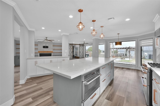 kitchen featuring stainless steel appliances, a center island, ornamental molding, white cabinets, and decorative light fixtures