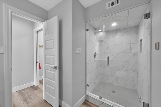 bathroom with hardwood / wood-style floors and a shower with door