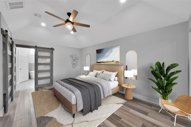 bedroom with hardwood / wood-style flooring, a barn door, lofted ceiling, and ceiling fan