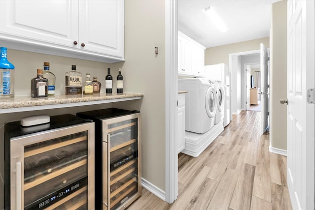 laundry room featuring cabinets, separate washer and dryer, light wood-type flooring, indoor bar, and beverage cooler