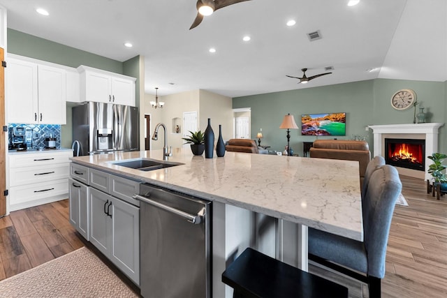 kitchen with stainless steel appliances, sink, a center island with sink, and white cabinets