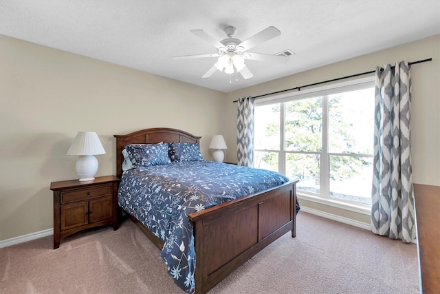 bedroom with ceiling fan, light carpet, and a textured ceiling