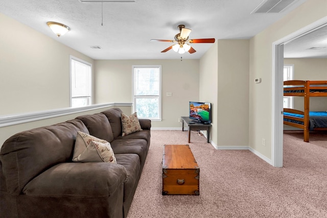 living room with ceiling fan, light carpet, and a textured ceiling