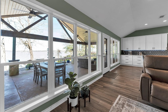 sunroom with lofted ceiling, plenty of natural light, ceiling fan, and a water view