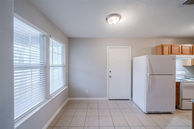 kitchen with light tile patterned flooring, white appliances, and a textured ceiling