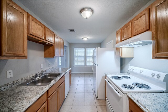 kitchen featuring sink, white appliances, light tile patterned floors, and a textured ceiling