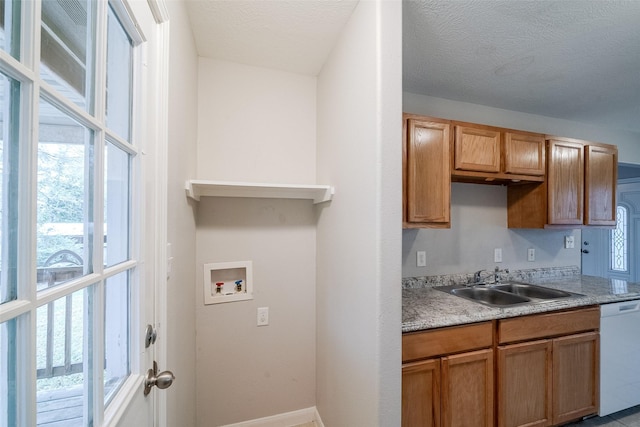 kitchen featuring dishwasher, sink, a textured ceiling, and a healthy amount of sunlight