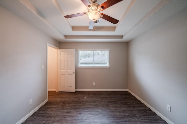 empty room featuring ceiling fan, dark hardwood / wood-style floors, and a raised ceiling