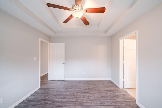 unfurnished room with a tray ceiling, wood-type flooring, and ceiling fan