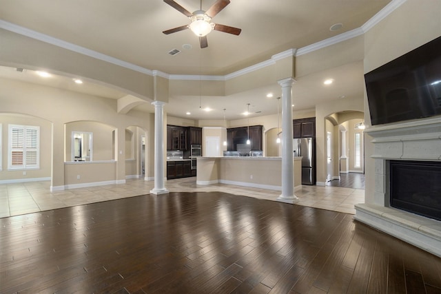 unfurnished living room featuring decorative columns, crown molding, ceiling fan, and light wood-type flooring