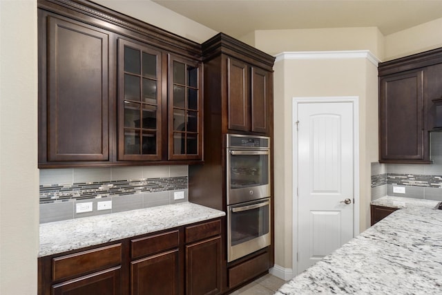 kitchen with tasteful backsplash, light stone countertops, and double oven