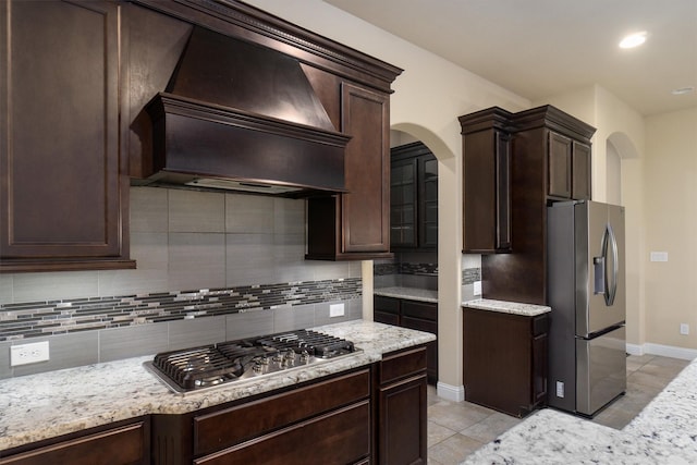 kitchen featuring tasteful backsplash, premium range hood, appliances with stainless steel finishes, and dark brown cabinets