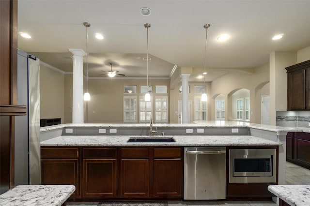 kitchen featuring decorative light fixtures, sink, stainless steel appliances, crown molding, and light stone countertops