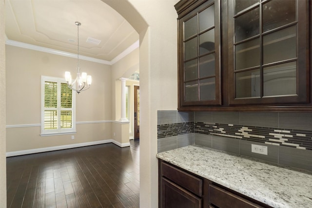 kitchen with dark hardwood / wood-style flooring, decorative backsplash, hanging light fixtures, light stone counters, and dark brown cabinets