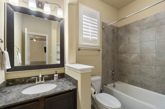 full bathroom with tiled shower / bath combo, vanity, ceiling fan, and toilet