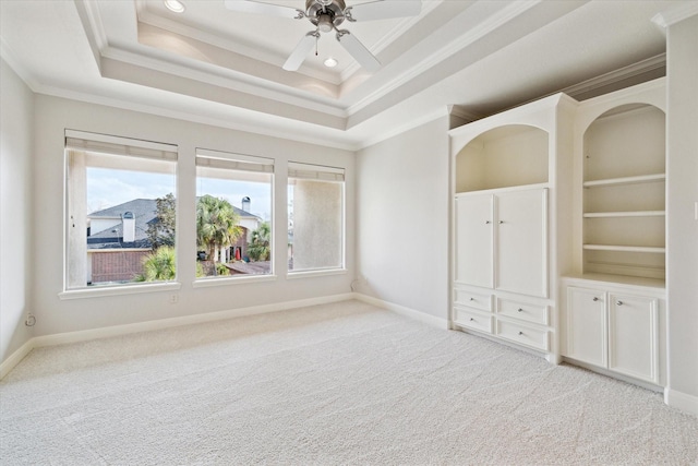 carpeted empty room with ceiling fan, ornamental molding, and a tray ceiling