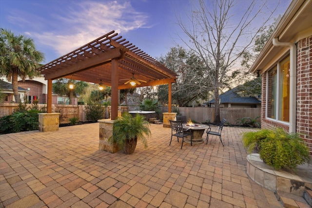 patio terrace at dusk with an outdoor fire pit, a pergola, and a fenced backyard