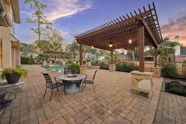 patio terrace at dusk featuring an outdoor fire pit and a pergola