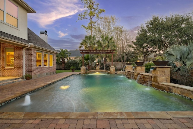 pool at dusk with pool water feature, a pergola, and a patio area