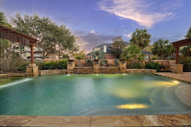 pool at dusk featuring pool water feature