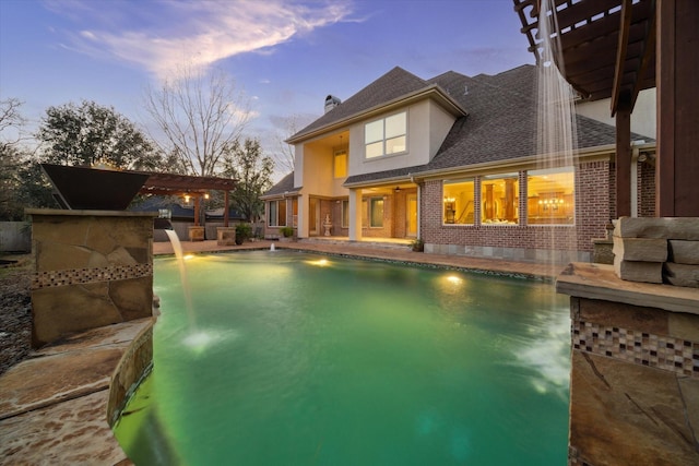 pool at dusk with a patio, a pergola, and pool water feature