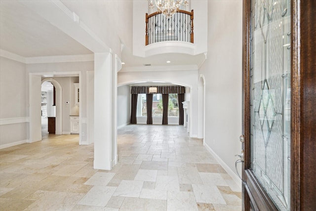 foyer with french doors, a towering ceiling, crown molding, and a chandelier