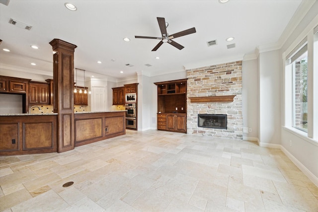 unfurnished living room featuring a stone fireplace, a wealth of natural light, and ornamental molding