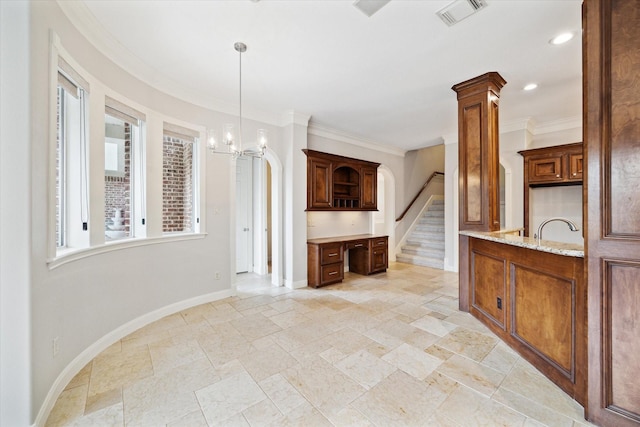 kitchen with crown molding, plenty of natural light, light stone countertops, and a notable chandelier