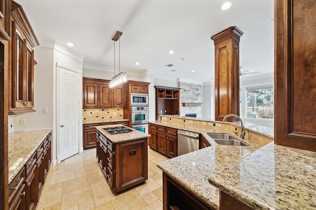 kitchen with pendant lighting, sink, appliances with stainless steel finishes, a center island, and light stone countertops