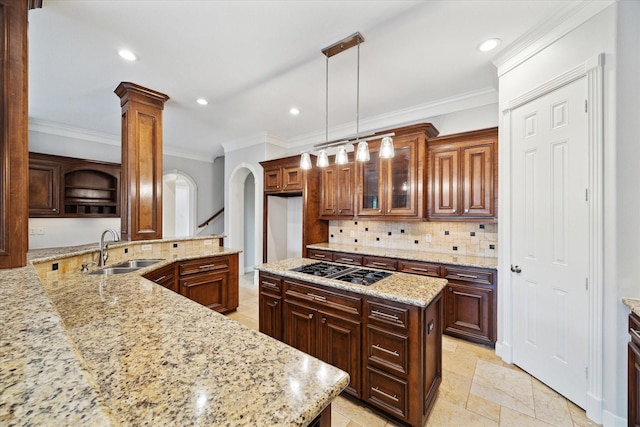 kitchen with sink, light stone counters, a center island, pendant lighting, and black gas cooktop